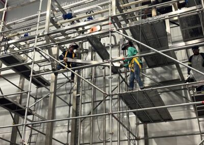 Workers on scaffolding inside industrial building.